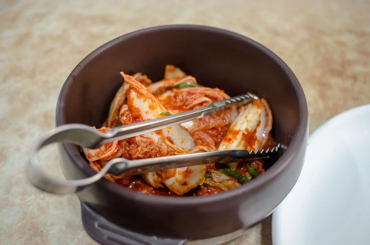 Bol de kimchi servi avec des pinces